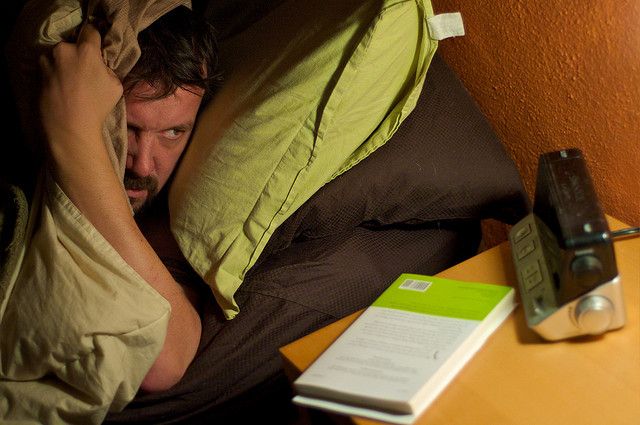 A hotel guest covering his ears while trying to sleep